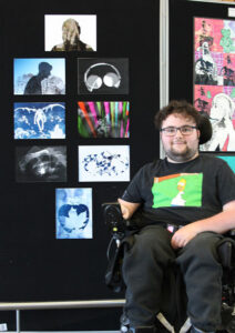 Student posing in front of his art works