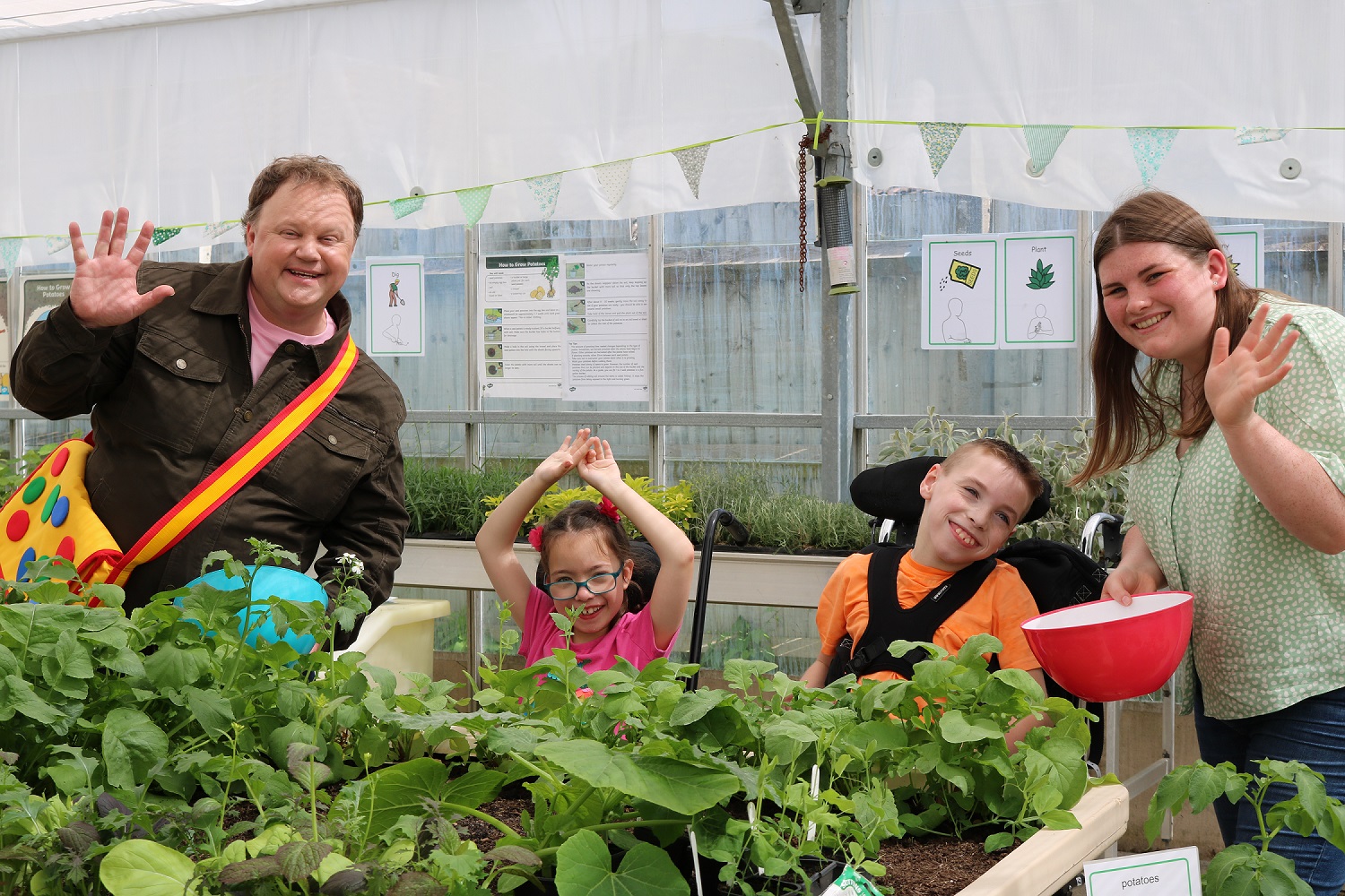Justin Fletcher with Treloar's primary students in the greenhouse filming for Something Special
