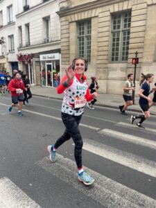 Lucy running the half marathon in Paris and waving to the photographer