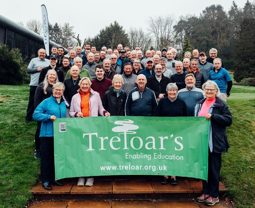 Group photo of golfers gathered at Old Thorns Hotel holding Treloar’s banner