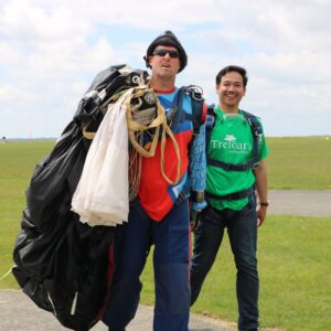 Treloar's staff member walking back after the skydive with the instructor next to him, carrying the parachute