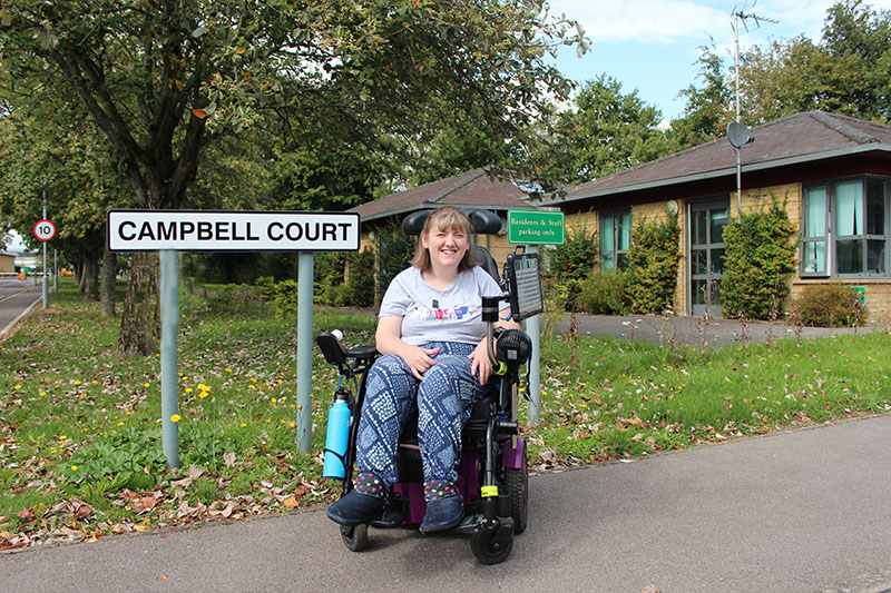 Campbell Court resident posing out the court, but the sign 'Campbell Court'