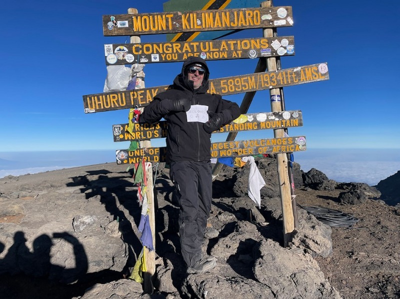 Chris reached the peak of Kilimanjaro - posing in front of a signpost