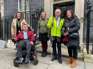 Treloar College student Ben with his assistant and Surrey Coalition of Disabled People outside Number 10 Downing Street