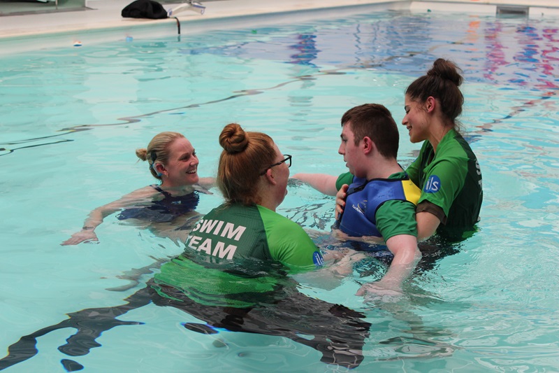 Suzanna Hext in the pool saying hello to Treloar's student who is being supported by to assistants.