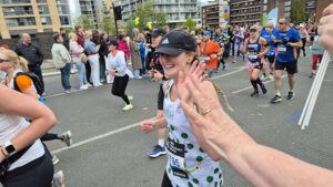 Hannah running the marathon and giving a high five to a person from the crowd.